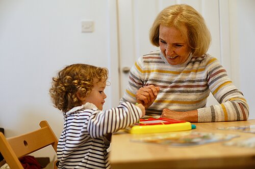 Susan Murray with a child drawing with a toy