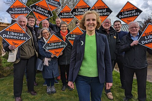 Susan Murray in front of Scottish Liberal Democrat activists holding orange diamonds