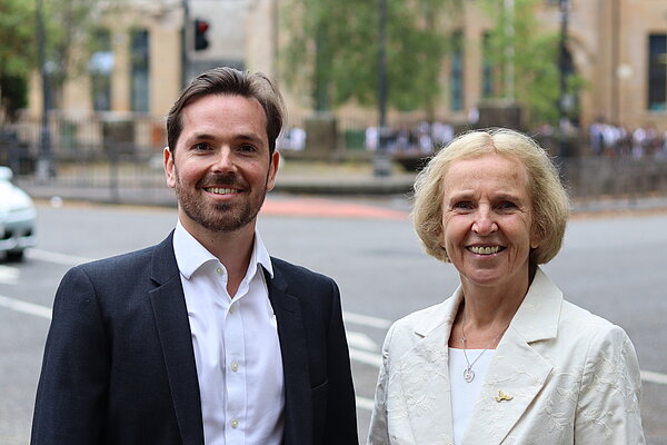 Adam Harley and Susan Murray standing together smiling with local street in the background