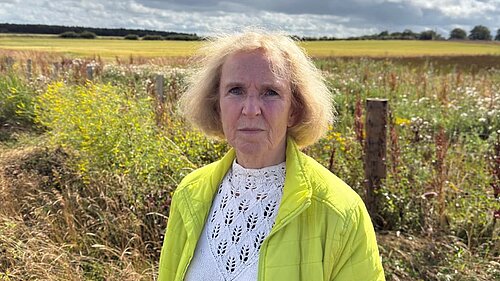 Susan Murray in front of green farmlands.
