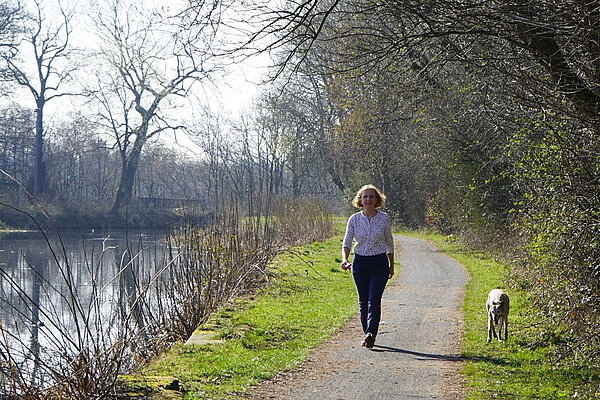 Susan Murray walking along a path by a river with a dog