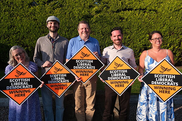 Ben Langmead in the centre of Lib Dem campaigners all holding up orange diamonds.