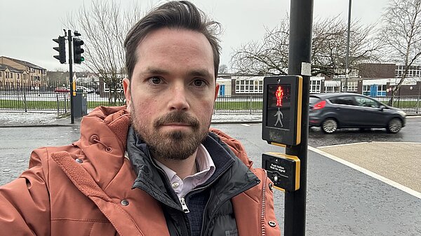 Adam Harley standing at a busy road where crossing patrollers were removed.