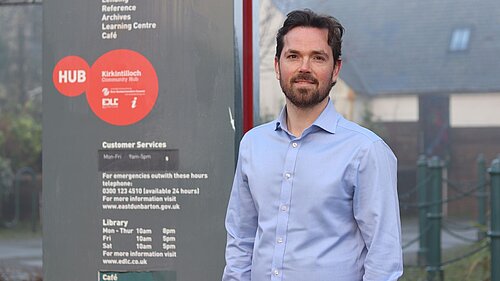 Adam Harley standing next to sign reading details for Kirkintillock Community Hub 