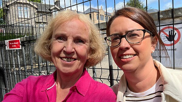 Susan Murray and Aileen Polson in front of a fence outside Milngavie Primary School.