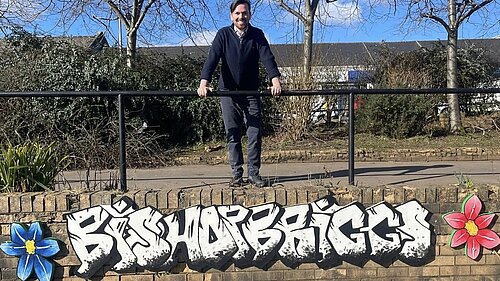Adam Harley leaning against a metal railing over a wall with graffiti art reading Bishopbriggs
