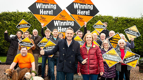 Alex Cole-Hamilton and Susan Murray in front of Lib Dem campaigners holding orange diamonds