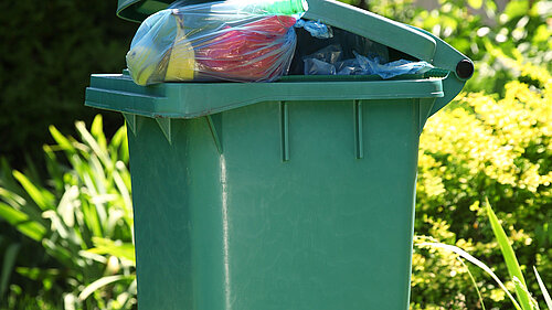 A wheelie bin overflowing with rubbish.